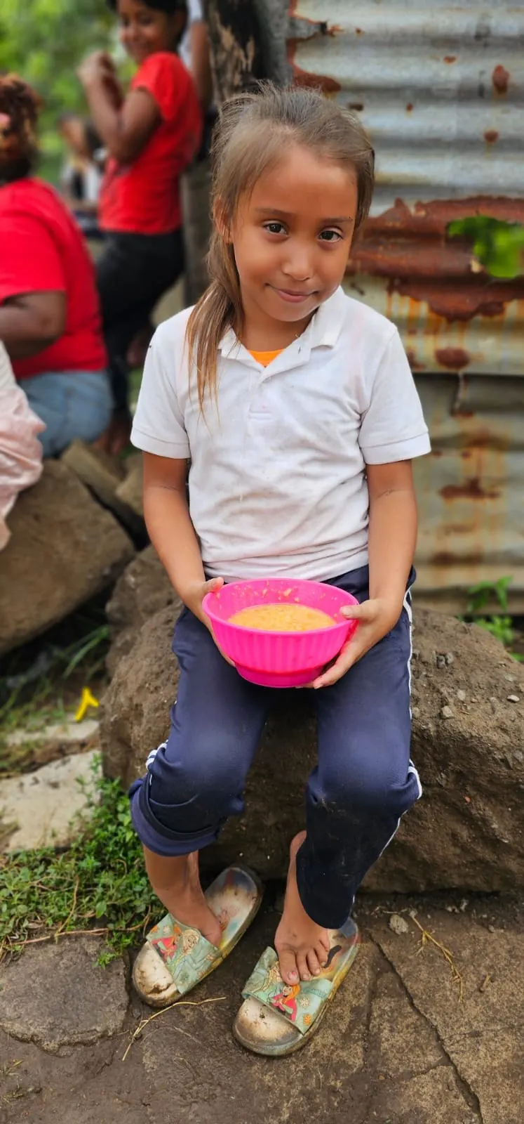 A girl holding a bowl of food through a feeding program in Nicaragua